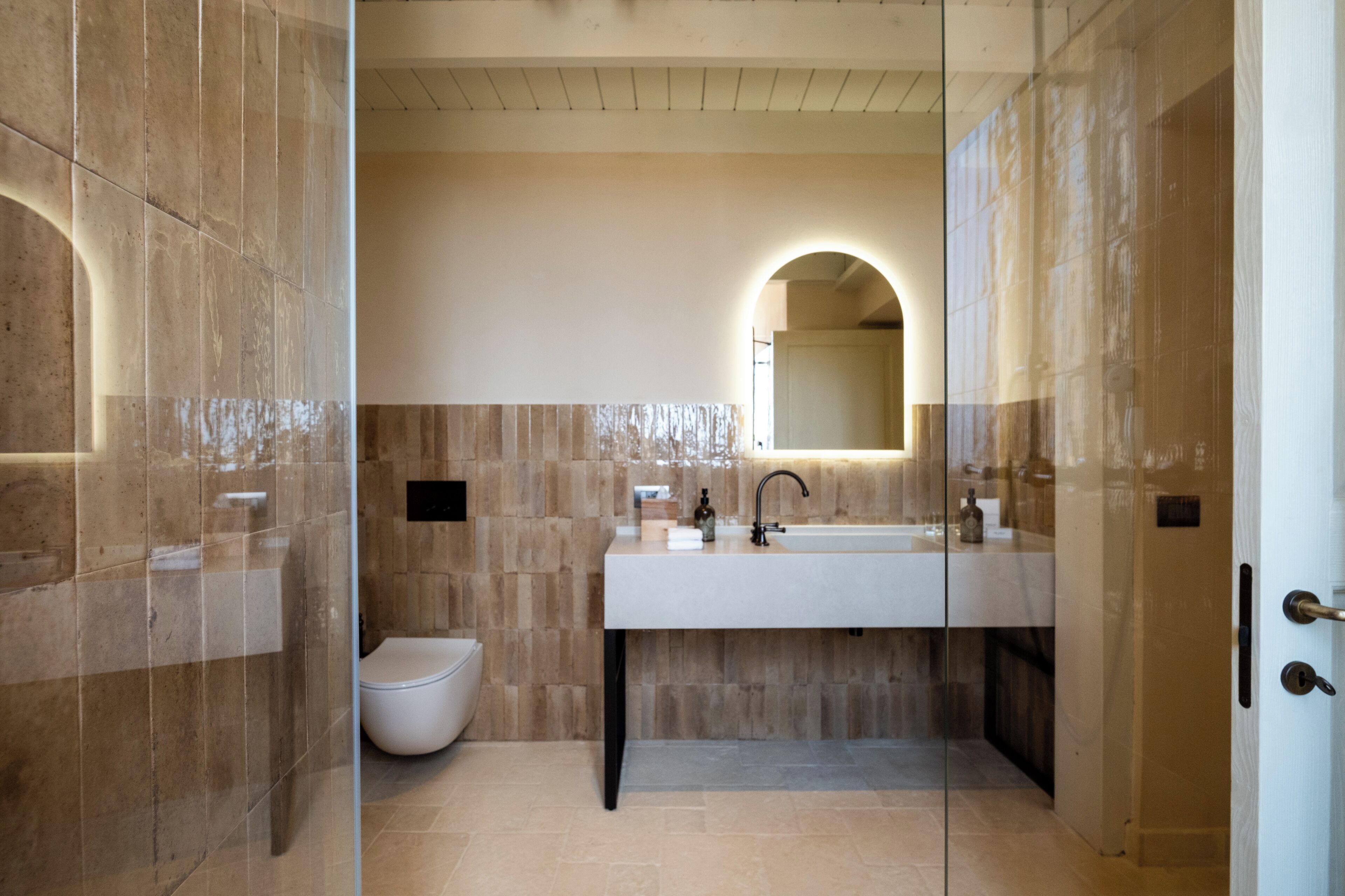 Un baño moderno con un lavamanos grande, un inodoro y una zona de ducha con mampara de vidrio.