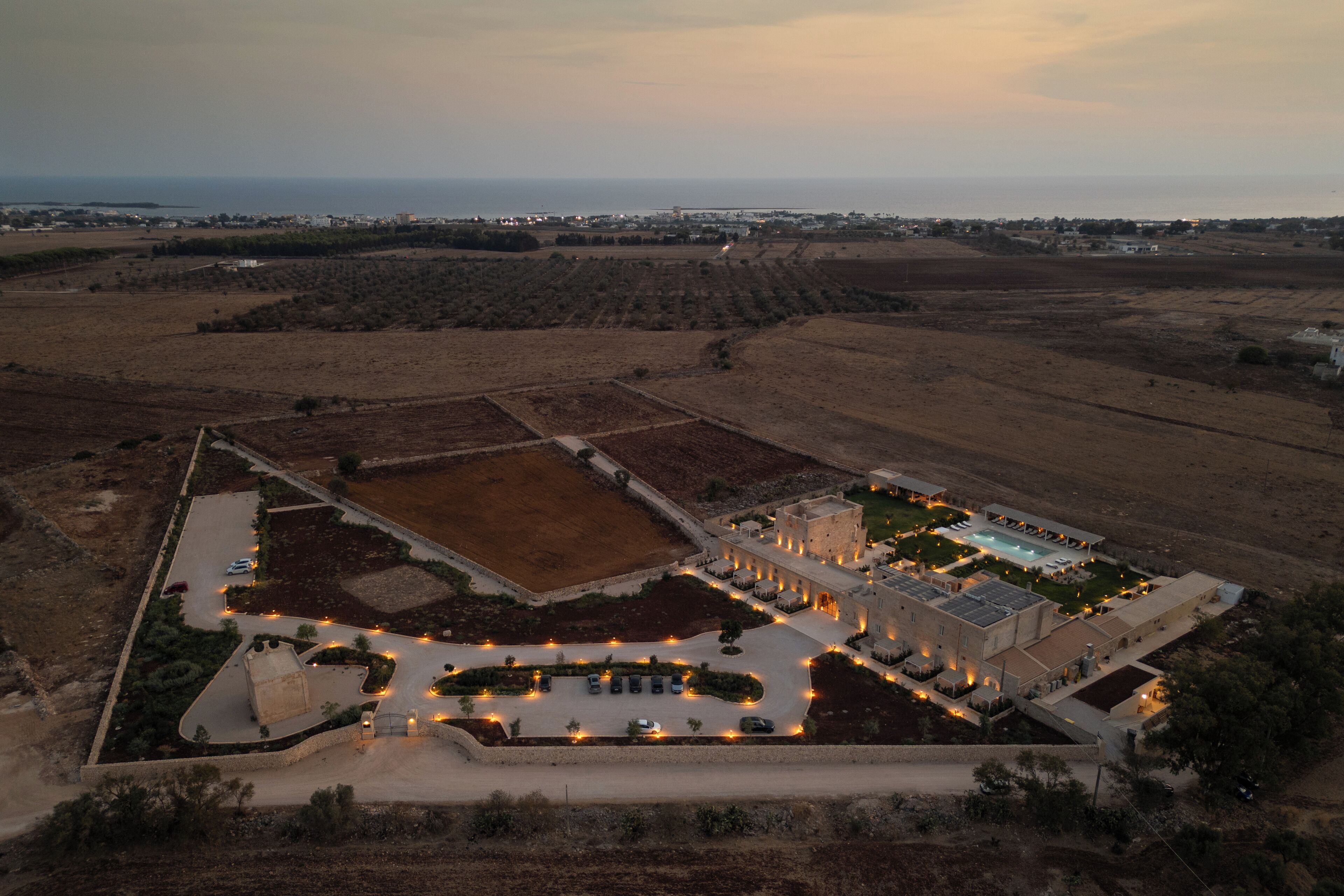 An aerial view of a resort with a swimming pool, multiple buildings, and landscaped areas.