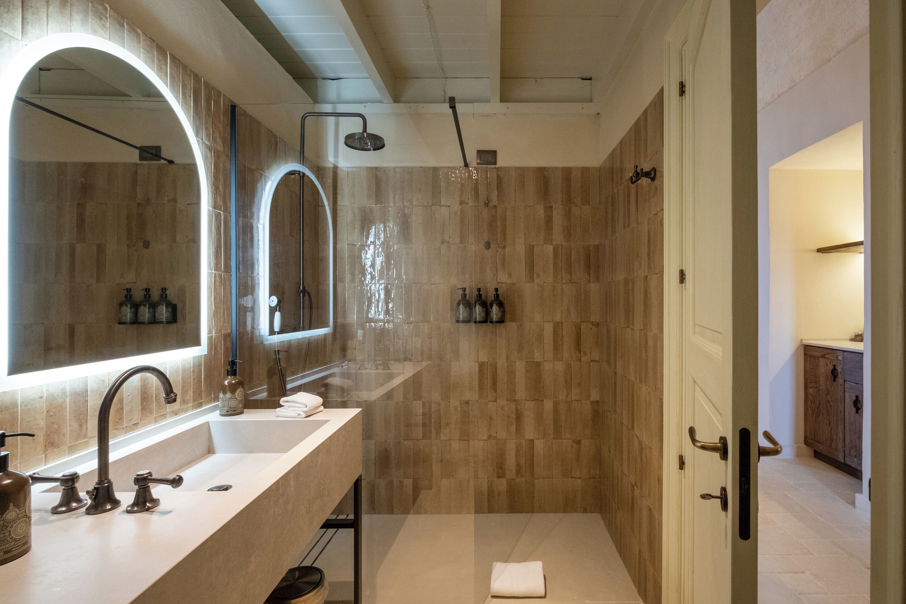 A modern bathroom with a large mirror, a sink, and a shower area.
