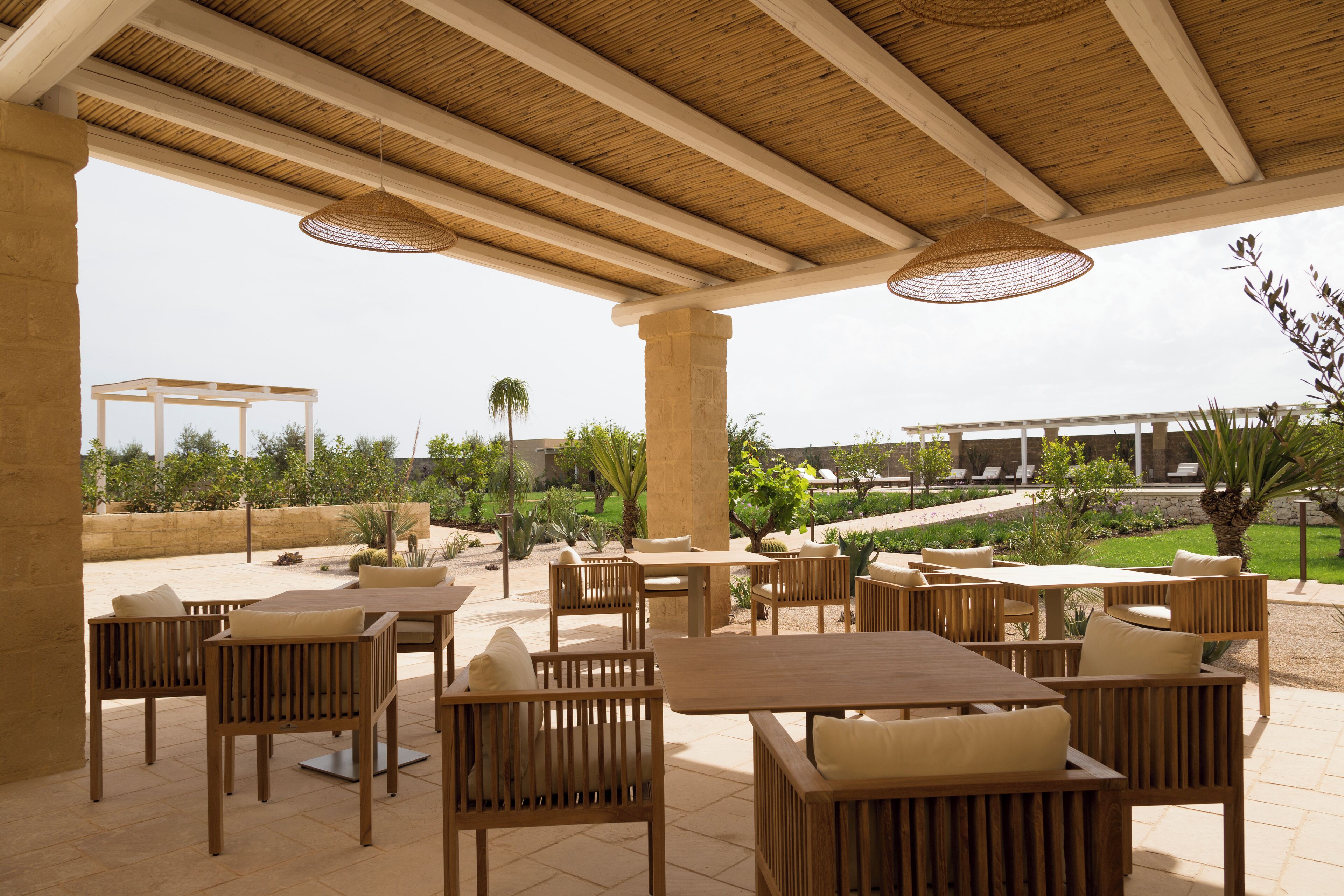 An outdoor patio area with wooden furniture and a view of a landscaped garden.
