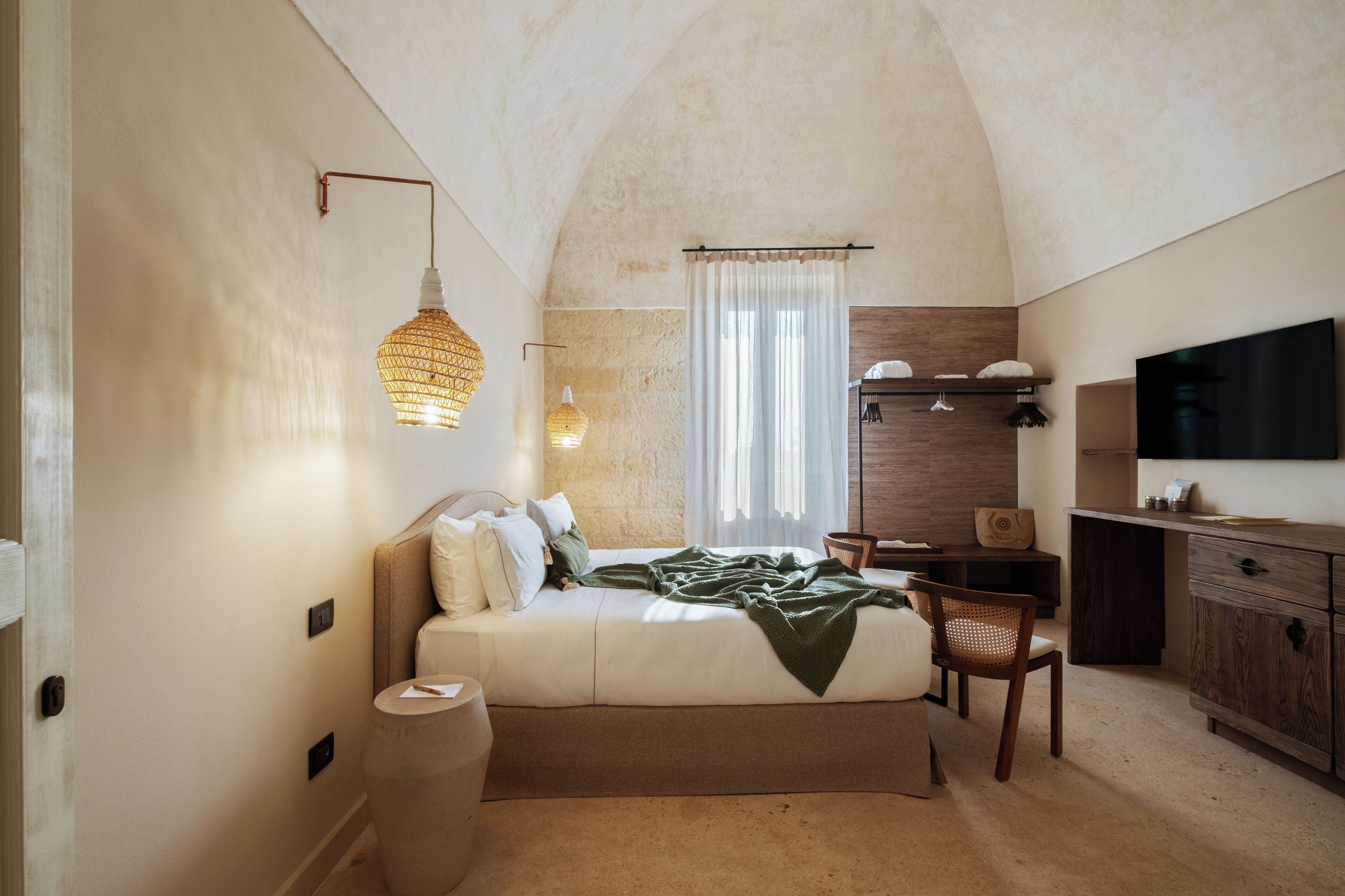 Een slaapkamer met een bed, nachtkastje, stoel en een televisie op een houten kast.