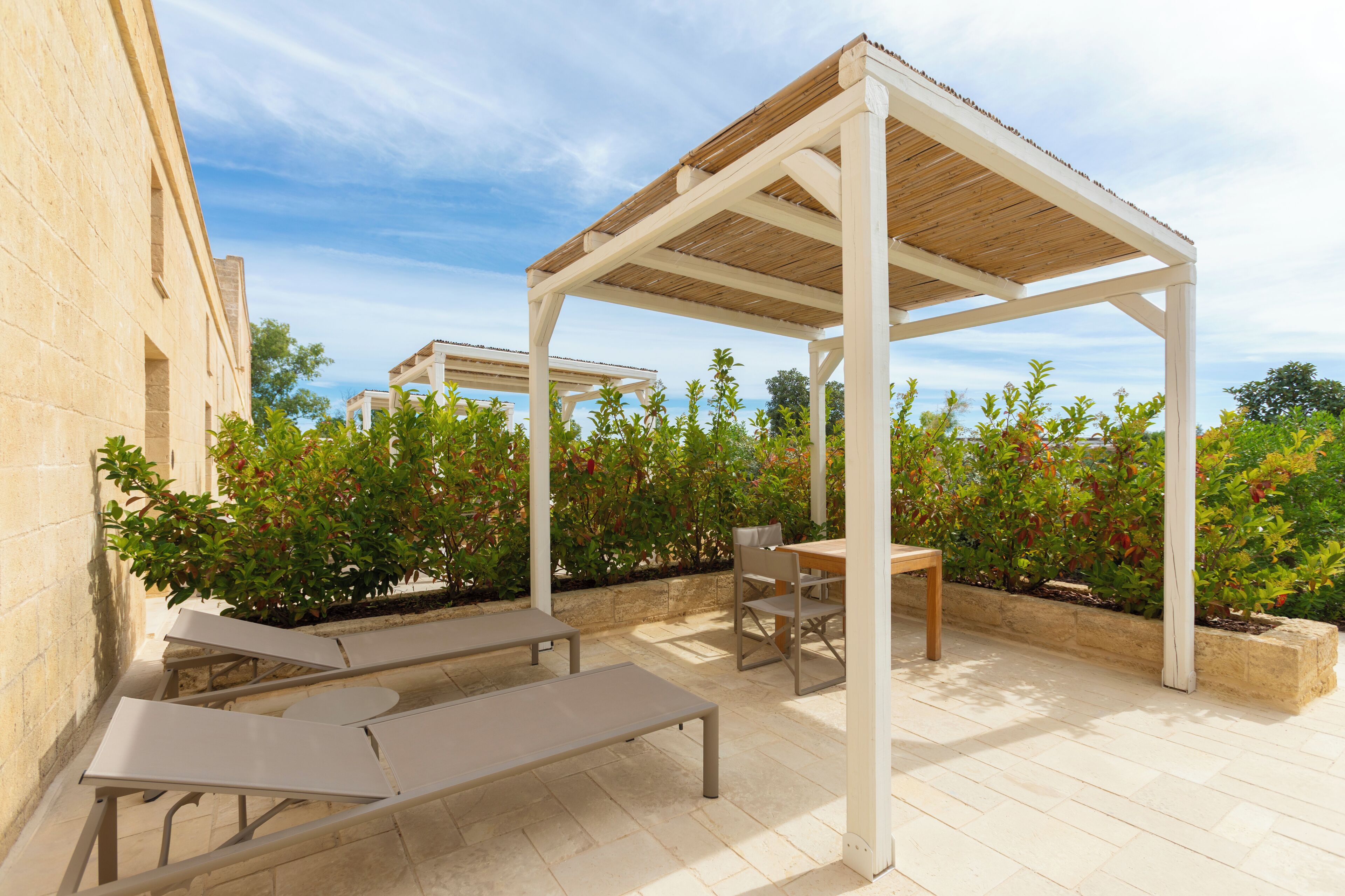 Un patio al aire libre con una pérgola, asientos y vista al mar.