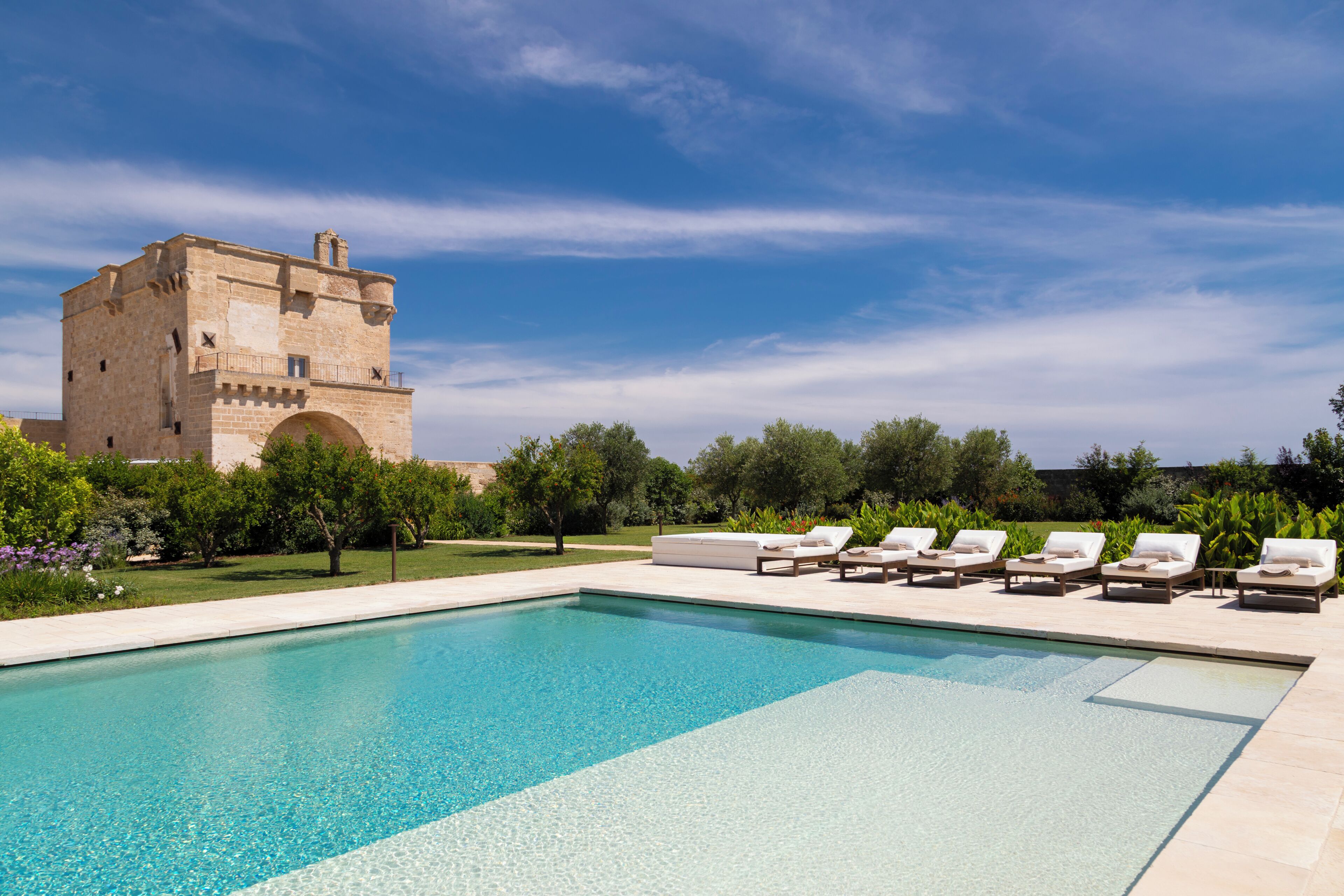 A swimming pool with lounge chairs and a historic building in the background.