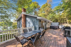 Une terrasse avec une table et des chaises, un barbecue et un téléviseur.