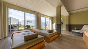 A modern hotel room with two beds, a large window with a view of the outdoors, and a small table with a plant. - Hotel Kiendl (Schenna)