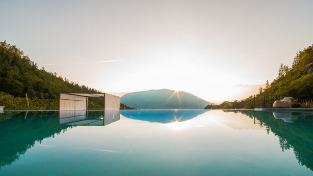 A tranquil infinity pool with a clear view of a mountain and lush greenery. - Hotel Kiendl (Schenna)