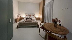 A bedroom with a bed, bedside tables, a nightstand, a wooden table with chairs, and a vase with flowers. - Design Penthouse with Hot Tub and Private Rooftop In Exarhia Athens (Athens)