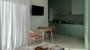 A compact living space with a dining area, kitchenette, and a TV mounted on the wall. - Design Penthouse with Hot Tub and Private Rooftop In Exarhia Athens (Athens)