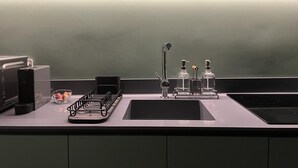 A modern kitchen with a black countertop, a sink, a coffee machine, and a dish rack. - Design Penthouse with Hot Tub and Private Rooftop In Exarhia Athens (Athens)