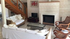 Ein Wohnzimmer mit Kamin, Fernseher und einer Wendeltreppe.