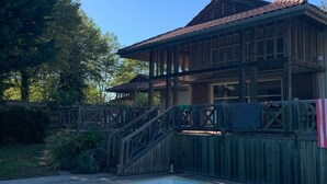 Ein Holzhaus mit Pool, umgeben von einer Holzterrasse und einem Zaun.