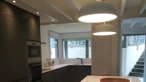 Eine moderne Küche mit dunklen Schränken, einer weißen Arbeitsplatte und einer Pendelleuchte.