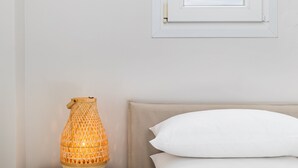 A bedroom with a bed, a nightstand with a lamp, and a window above the bed. - Sunflower by halu! Apartments (Thessaloniki)