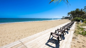 Una spiaggia con una passerella in legno e file di sedie vuote.