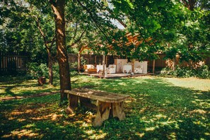 A wooden bench in a garden with a pergola and outdoor furniture. - Marta 8 - House & Garden (Tallinn)