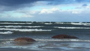 Una playa con olas y dos rocas grandes en el agua.