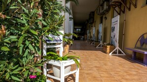 Um corredor com plantas em vasos, uma placa indicando um hostel e piso de azulejos.