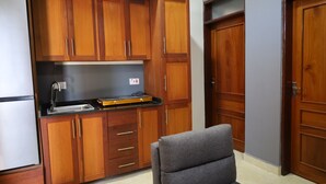 Una cocina con armarios de madera, un sofá gris y una puerta cerrada.