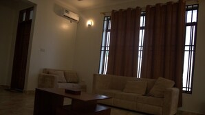 Una sala de estar con sofá, mesa de centro y ventana con cortinas.