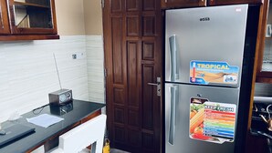 Una cocina con refrigerador de acero inoxidable, armarios de madera y salpicadero de azulejos blancos.