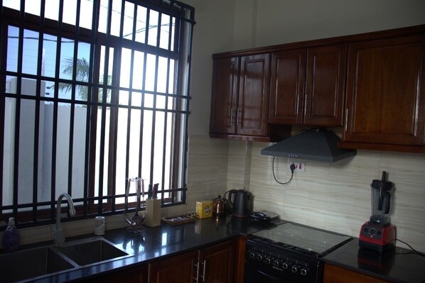 A kitchen with wooden cabinets, a stove, a sink, and a window with bars.