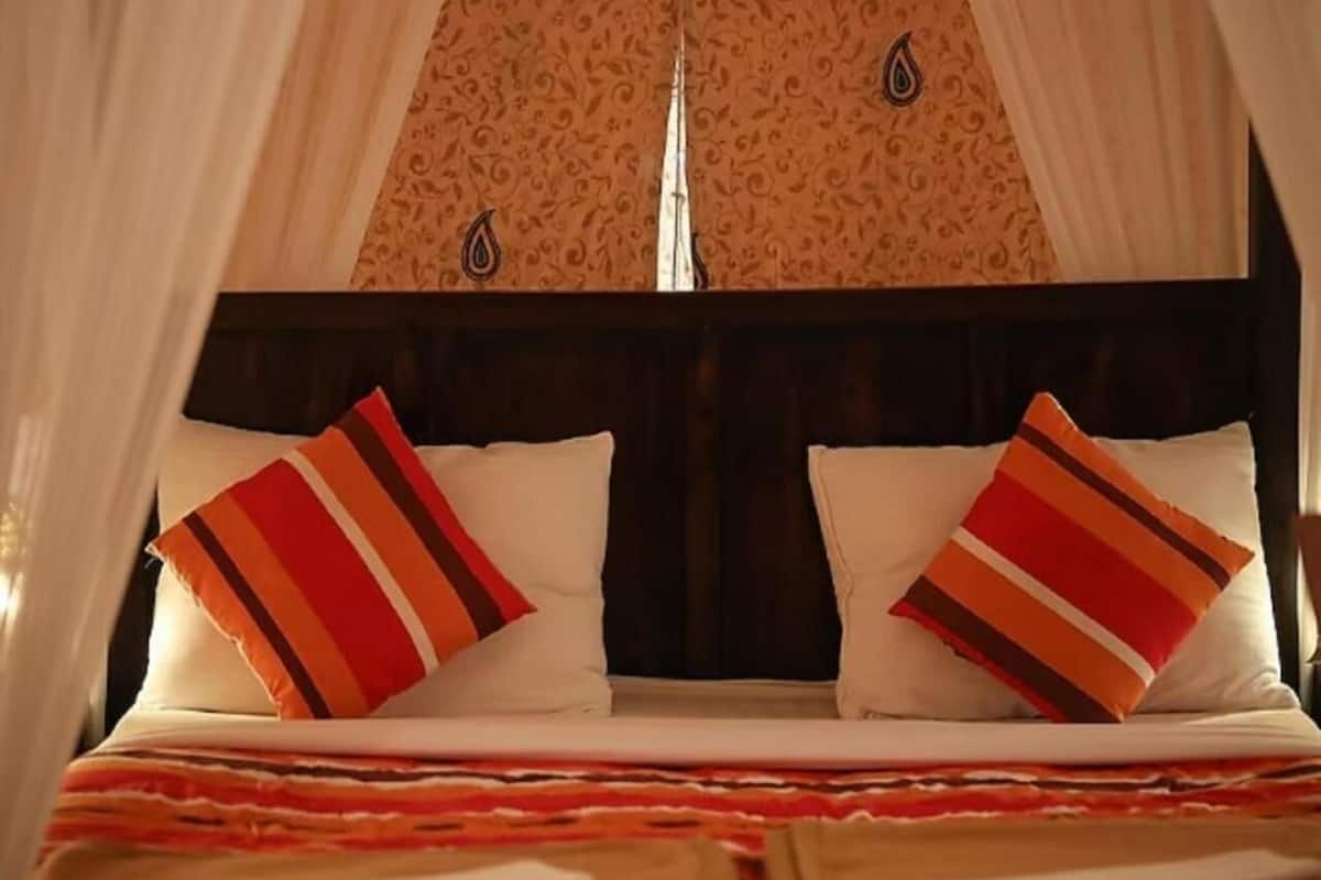 Ein Bett mit zwei Kissen, einer gestreiften Decke und einem Baldachin.