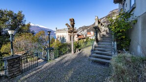 Un chemin menant à un bâtiment doté d’un escalier en pierre, avec une montagne en arrière-plan.