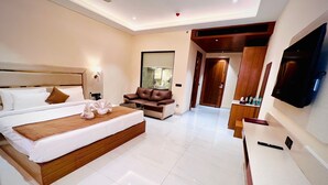 A modern hotel room with a large bed, a sofa, a TV, and a desk. - The Velvista Hotel (Muzaffarnagar)