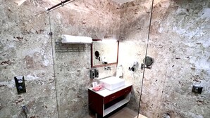 A modern bathroom with a glass-enclosed shower, a marble wall, a sink with a mirror, and a white cabinet. - The Velvista Hotel (Muzaffarnagar)