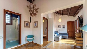 A spacious living area with a glass shower, a blue chair, a sofa, and a wooden ceiling. - Solemar Sicilia - Casa Ernesto  (Santa Flavia)