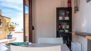 A room with a dining table, chairs, a bookshelf, and a potted plant. - Solemar Sicilia - Casa Ernesto  (Santa Flavia)
