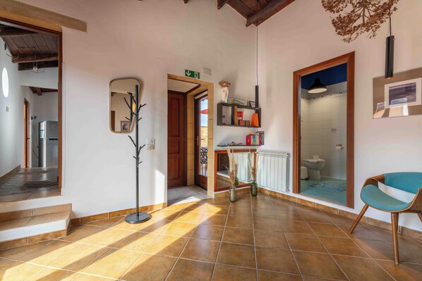 A hallway with a mirror, a door leading to a bathroom, and a chair. - Solemar Sicilia - Casa Ernesto (Santa Flavia)
