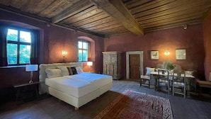 A bedroom with a large bed, wooden ceiling beams, a window, a desk, and a chair. - Ansitz Zinnenberg (Appiano Sulla Strada del Vino)