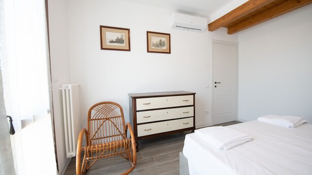 Ein Schlafzimmer mit einem Bett, einer Kommode, einem Schaukelstuhl und zwei gerahmten Bildern an der Wand.