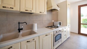 A kitchen with beige cabinets, a gas stove, an oven, and a microwave. - Oasi del Garda (Manerba del Garda)