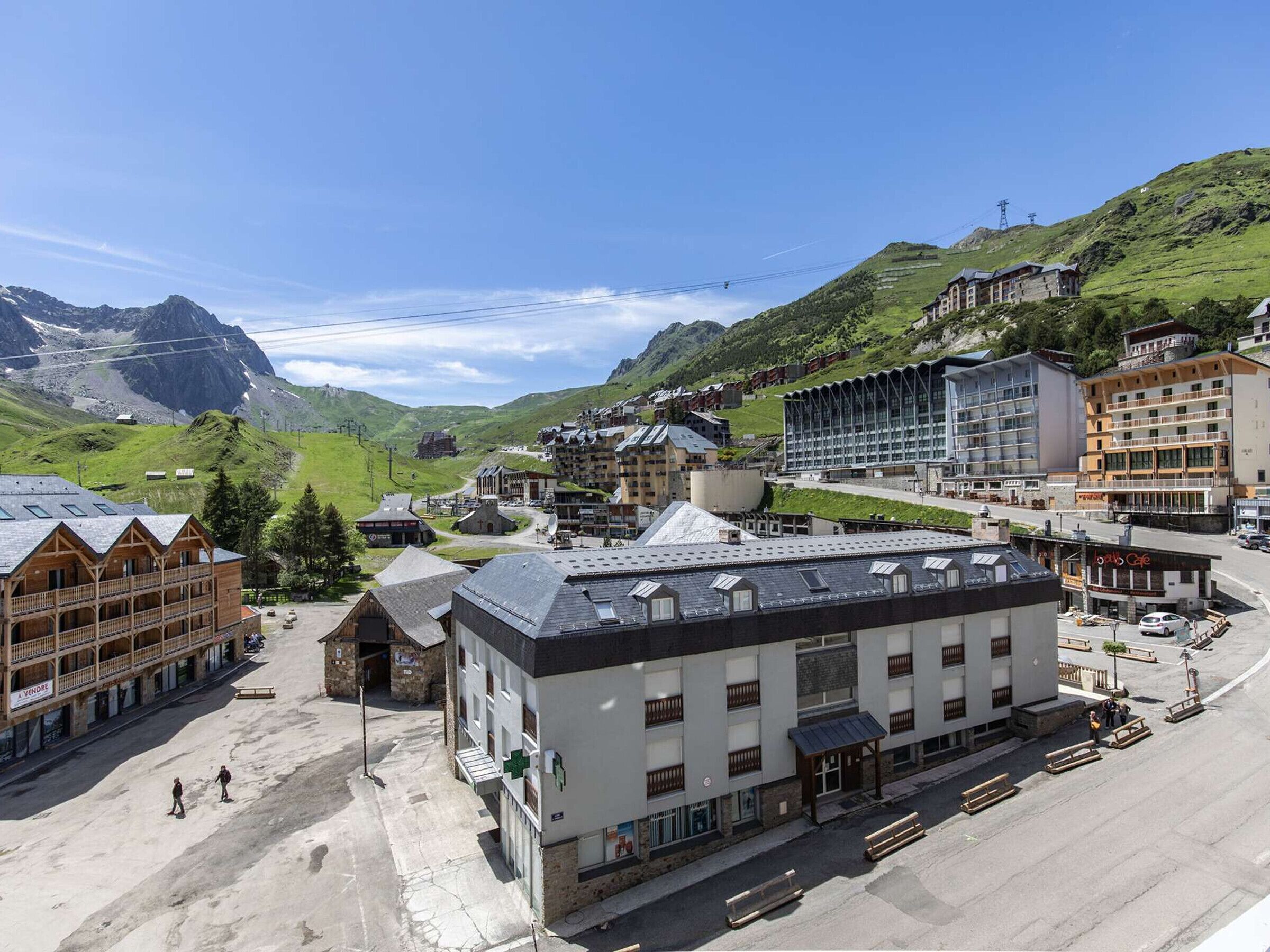 A town with a mix of traditional and modern buildings, a central square, and a mountainous backdrop.