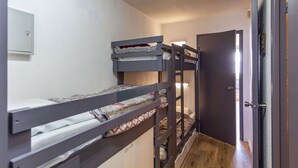 A bunk bed room with a door to the right and a light switch on the wall.