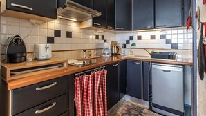 A compact kitchen with dark cabinets, a toaster, a kettle, and a dishwasher.