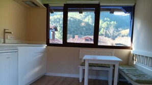 A small kitchen with a window, a white table, and a bench. - Vivienda 2 Personas Finca Malvasia (Cabezón de Liébana)