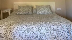 A bedroom with a bed, a nightstand, and a hanging light fixture. - Vivienda 2 Personas Finca Malvasia (Cabezón de Liébana)