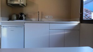A compact kitchen with a dishwasher, a microwave, and a coffee maker on the counter. - Vivienda 2 Personas Finca Malvasia (Cabezón de Liébana)