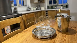 A wooden dining table with a metal tray holding several empty wine glasses and a bottle of champagne in a metal bucket.