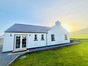 A white house with a sloped roof, a chimney, and a large window. - Cottage in Ballintoy, Causeway Coast - sleeps 5 (Ballintoy)