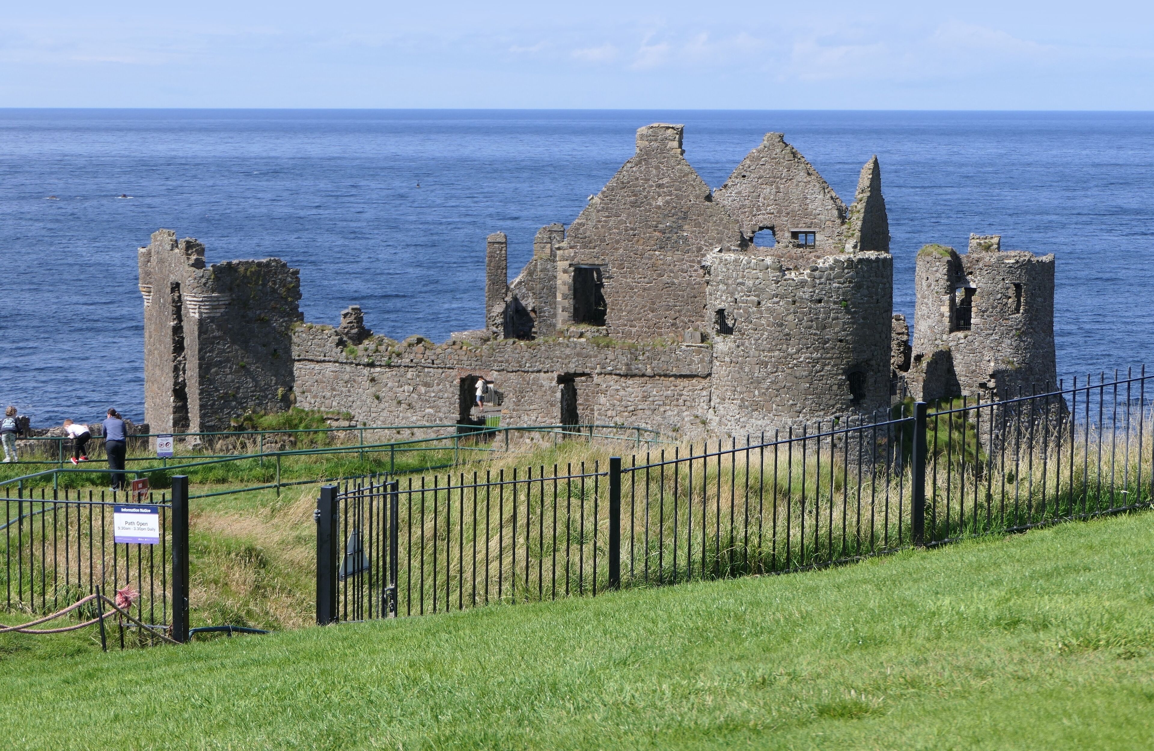 Un château de pierre historique, avec un parterre verdoyant et une vue sur la mer.
