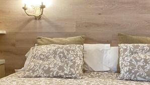A bed with patterned bedding and two pillows, a nightstand, and a wall-mounted light fixture.