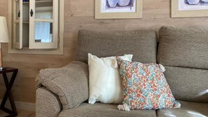 A beige sofa with two pillows, a wooden cabinet with glass doors, and framed artwork on the wall.