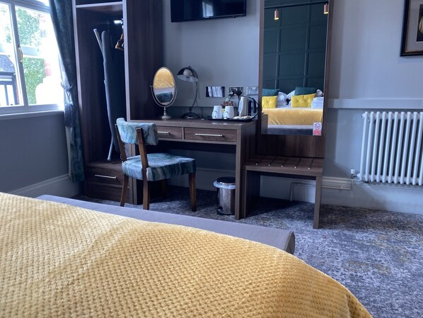 A hotel room with a bed, a desk with a chair, a mirror, a radiator, and a window with curtains. - The Bootham Tavern - York  (York)