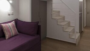 Una sala de estar moderna con un sofá púrpura, una escalera y un diseño minimalista.