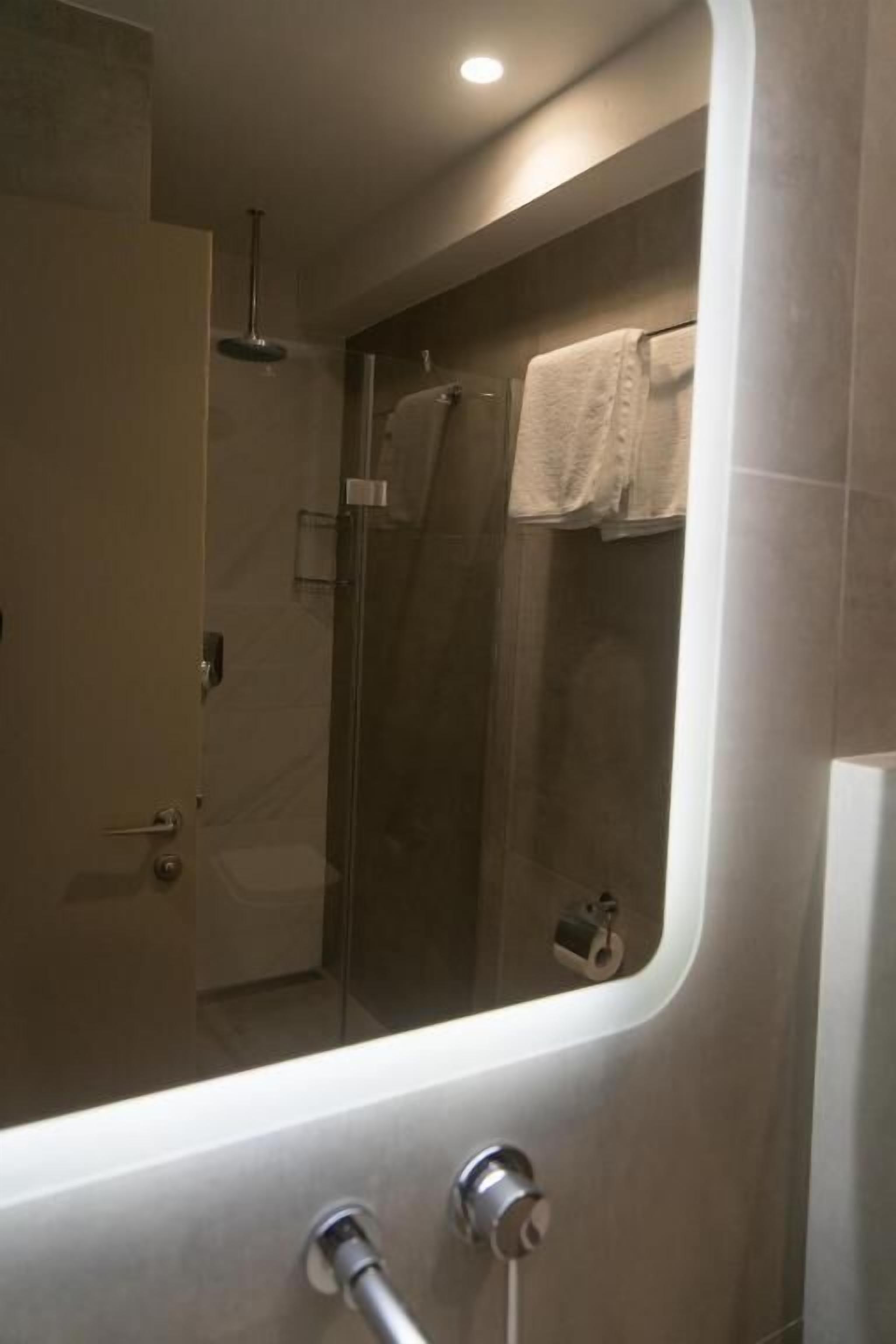 A modern bathroom with a glass-enclosed shower, a visible towel rack, and a bathtub.