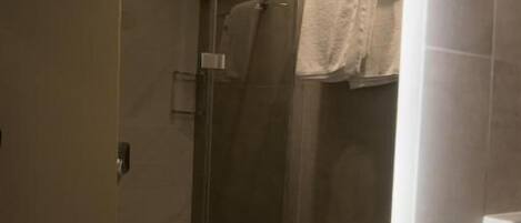 A modern bathroom with a glass-enclosed shower, a visible towel rack, and a bathtub.